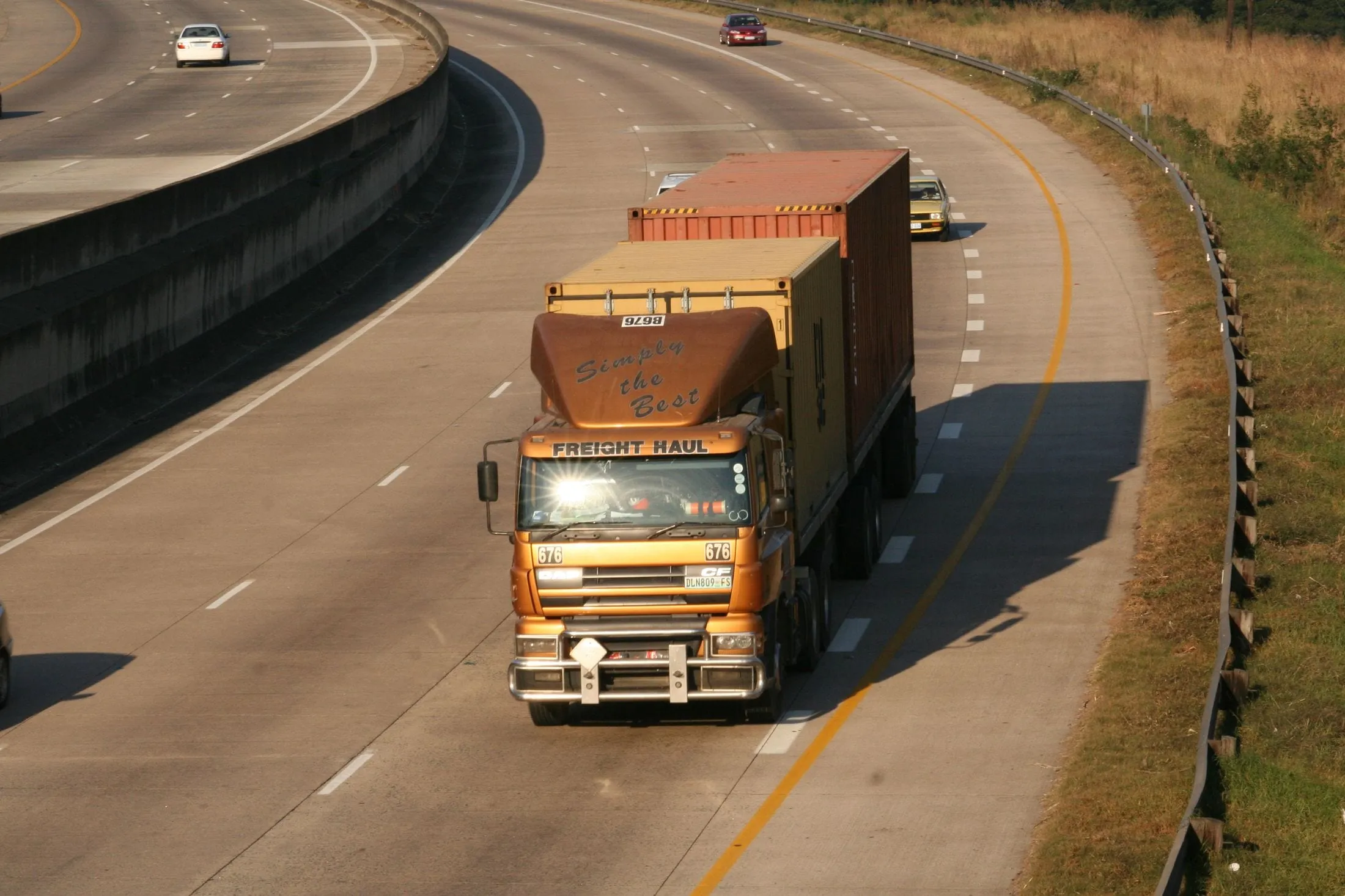 Container truck driving along a curving highway
