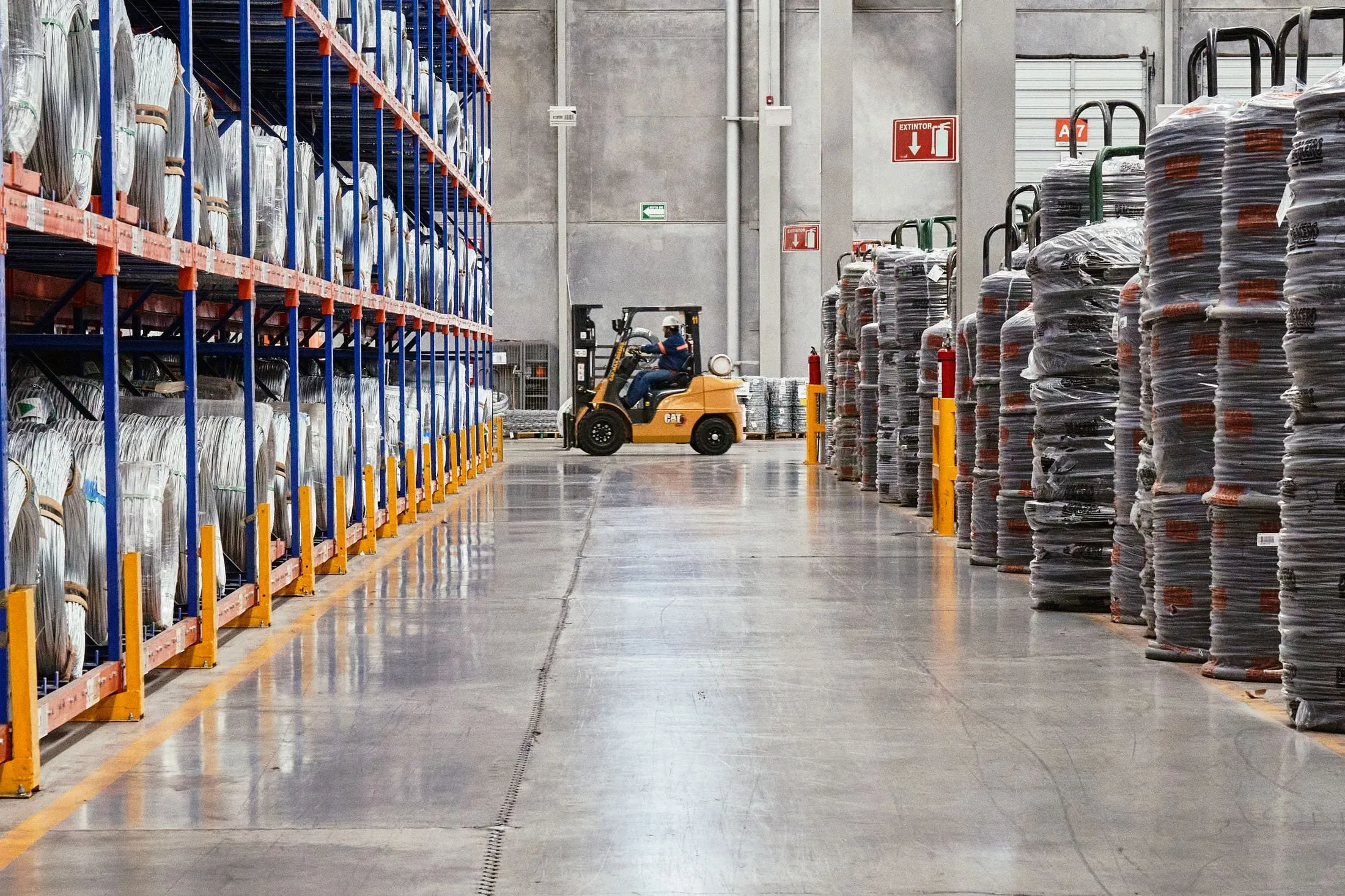 Forklift moving through a warehouse aisle lined with pallet racking